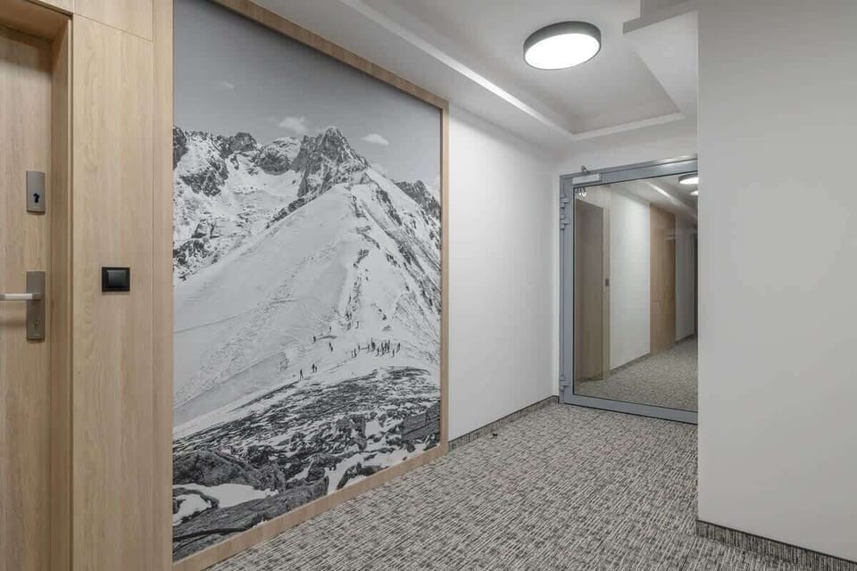 A corridor with stylish wall art depicting mountain landscapes, illuminated by soft ceiling lights, creating a modern and artistic ambiance.

