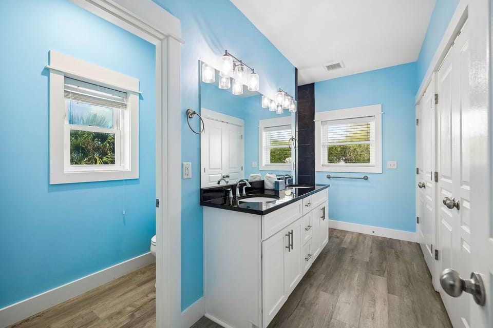 Freshen up in your bright, coastal-inspired bathroom with dual sinks, sleek black countertops, and crisp white cabinetry—perfect for getting ready together.