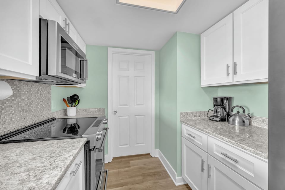 Your fully equipped galley kitchen features granite countertops, white cabinetry, and everything needed to prepare meals during your stay.