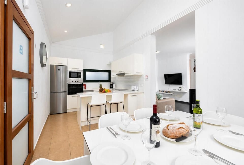 Open-plan living room with sofa, dining area, kitchen, ornamental fireplace, A/C, WiFi internet, and satellite TV