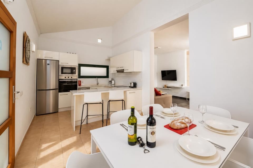 Open-plan living room with sofa, dining area, kitchen, A/C, WiFi internet, and satellite TV