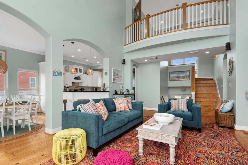 Open living room with balcony access, loft overlook, and abundant natural light.