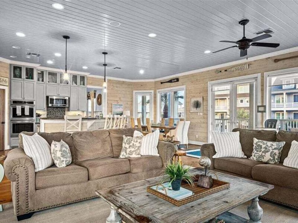Spacious open living area with sectional sofa, ceiling fan, and natural light—luxury Galveston vacation rental.