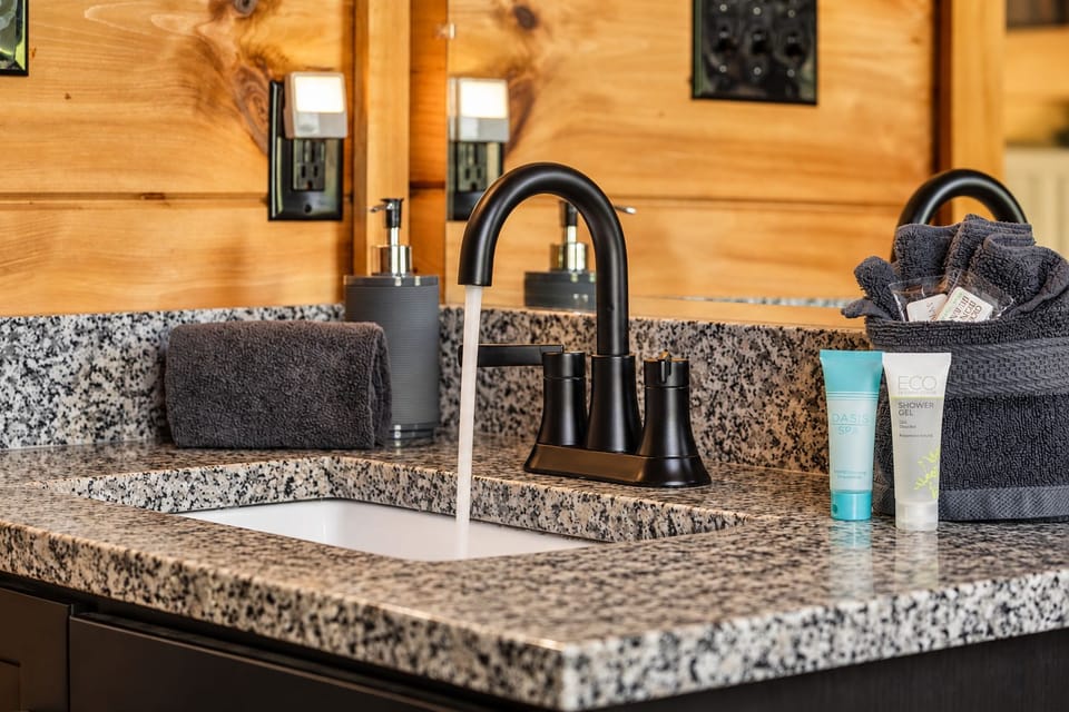 Rolled hand towels, shampoo, shower gel, and a soap pump ready at the vanity.