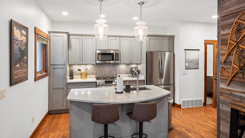 The fully stocked kitchen features custom cabinetry, marble countertops, high-end appliances, and an island/breakfast bar with seats for two