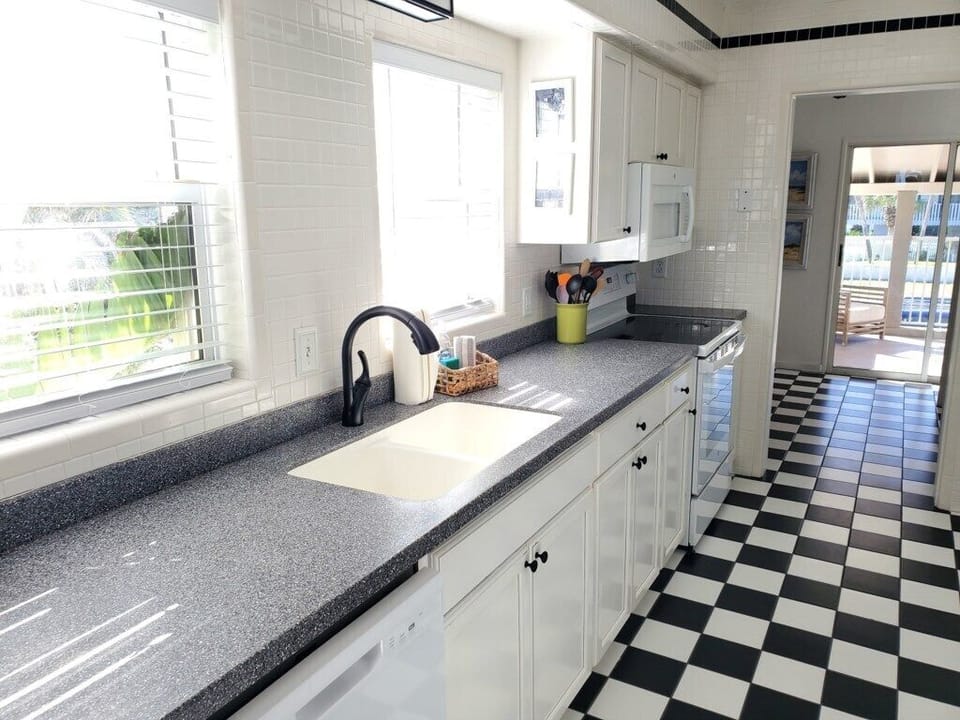 Sunny kitchen with checkered floors and spacious countertops.