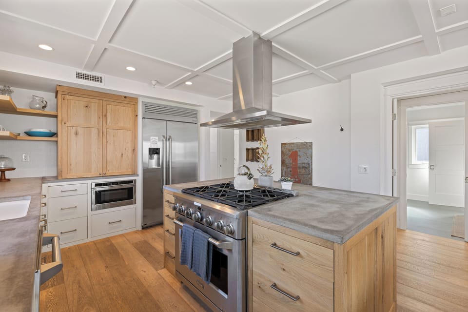 Newly Remodeled featuring high-end Appliances, sleek countertops, and a central Island with an integrated Stove, this open-plan modern Kitchen is both stylish and functional, with ample seating for casual Dining.