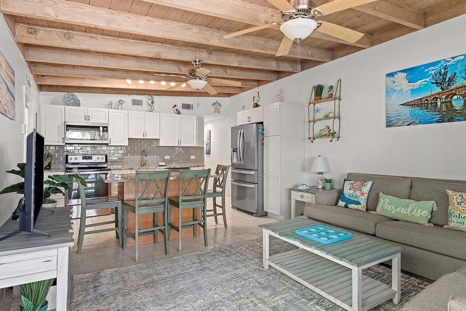 The welcoming great room connects the kitchen, dining area, and comfortable lounge beneath charming exposed wood ceilings.
