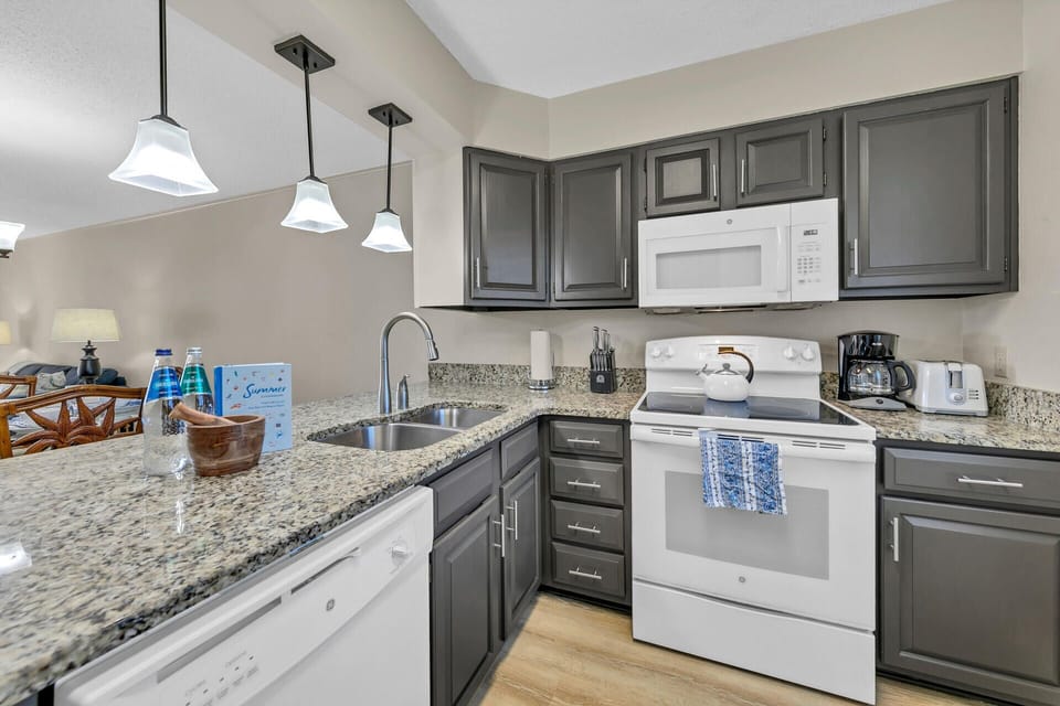 Your fully equipped kitchen awaits with granite counters, stylish pendant lighting, and everything you need to create memorable meals.