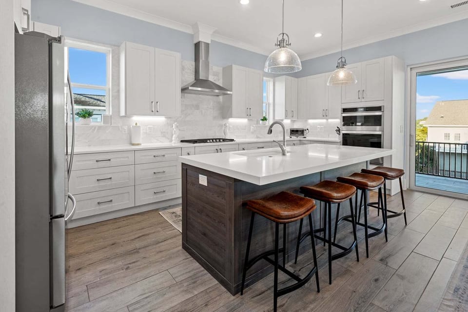 Kitchen island with bar stools and white cabinetry at Vistas Del Sol, a Tilghman Beach vacation rental