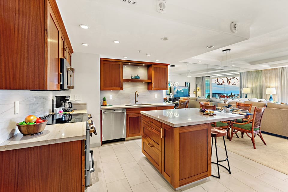 Bright and inviting open-concept kitchen featuring warm wood cabinetry, sleek granite countertops, and a spacious island that flows seamlessly into the living and dining areas. Perfect for entertaining or relaxing in comfort.