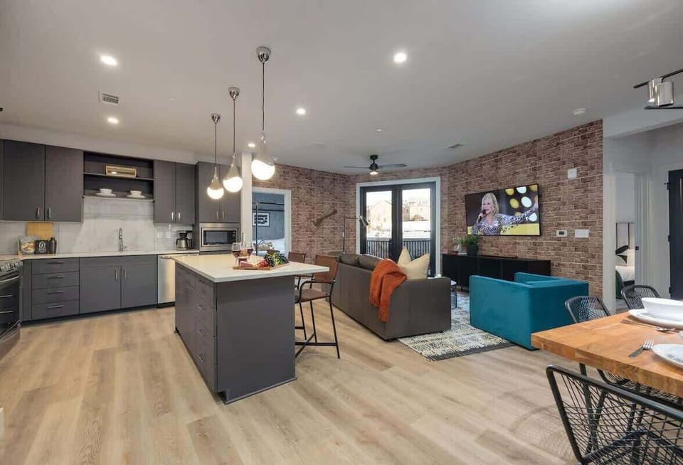 Bright open-concept living space featuring comfortable seating, smart TV, designer furnishings, and access to the private patio.