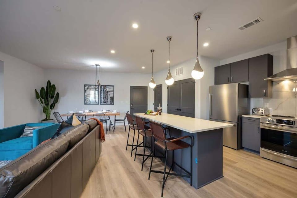 Fully equipped kitchen stocked with basic cooking essentials, stainless steel appliances, and breakfast bar seating, all connected to the dining area.