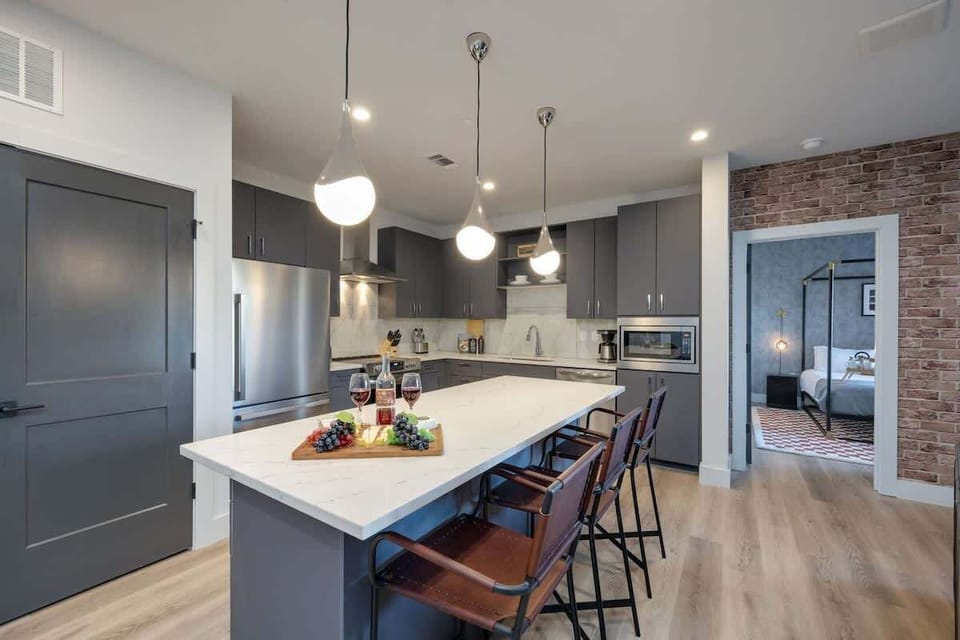 Fully equipped kitchen stocked with basic cooking essentials, stainless steel appliances, and breakfast bar seating, all connected to the dining area.