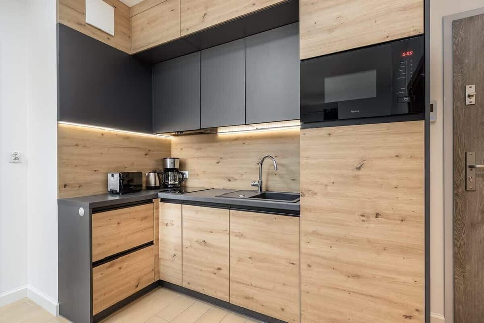A fully equipped kitchen with wooden cabinets, black countertops, and modern appliances, blending functionality with style.

