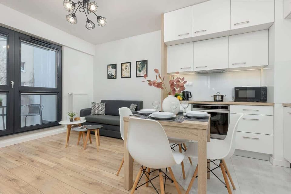 A combined living and dining area with a modern kitchen, gray furniture, and light wooden flooring for a bright, airy look.

