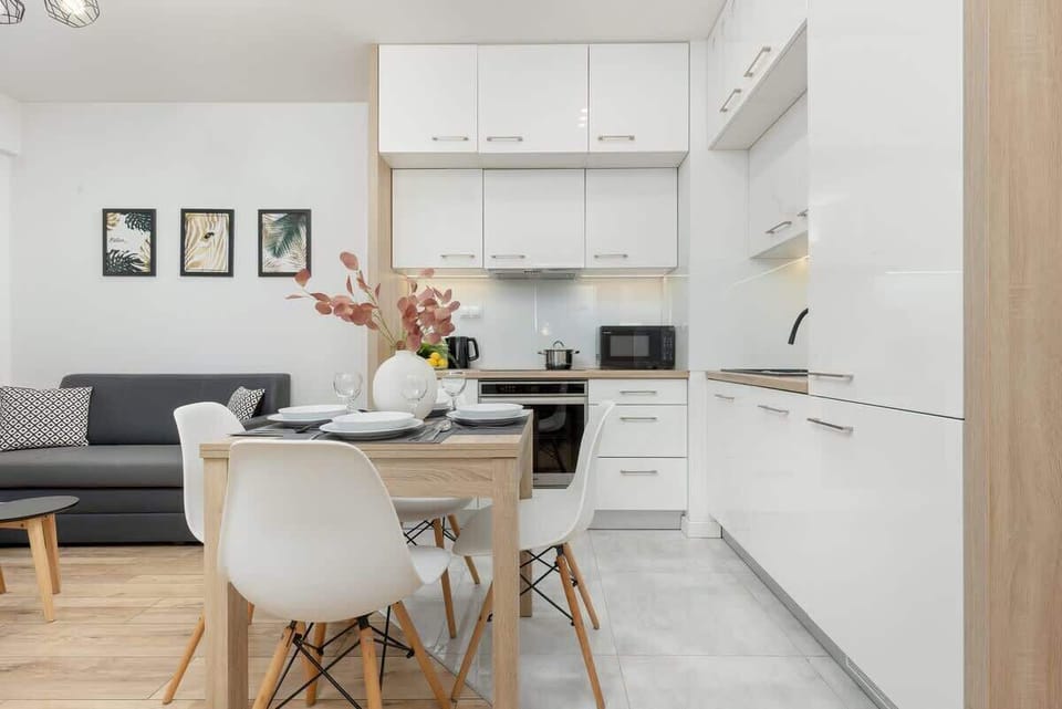 An open-plan living and dining area with a gray sofa, white dining set, and chic decor, maximizing the use of space.

