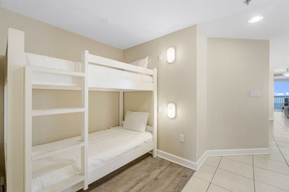 Compact bedroom featuring a white bunk bed with clean lines and soft lighting for a cozy atmosphere.
