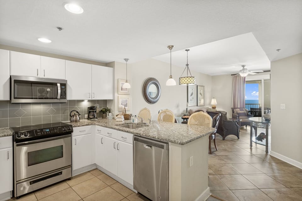 Modern kitchen with granite countertops and stainless steel appliances overlooking the living area and ocean view.