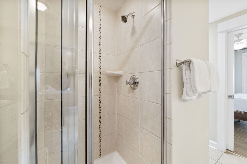 Modern tiled shower with glass door and chrome fixtures