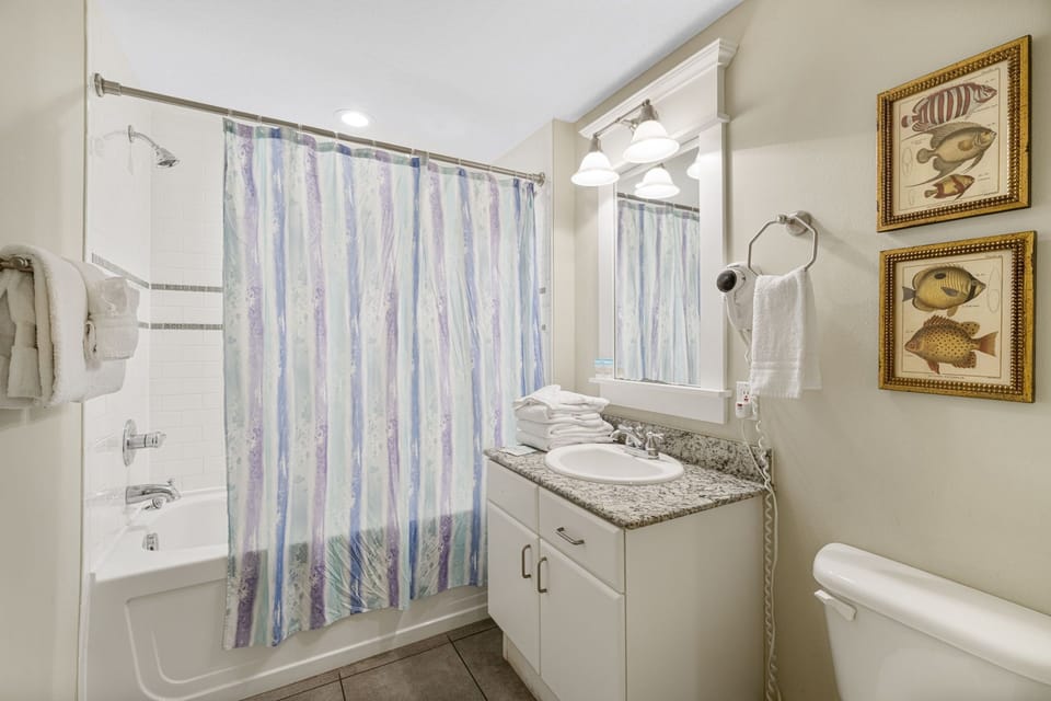 Clean bathroom with granite countertop and shower-tub combination