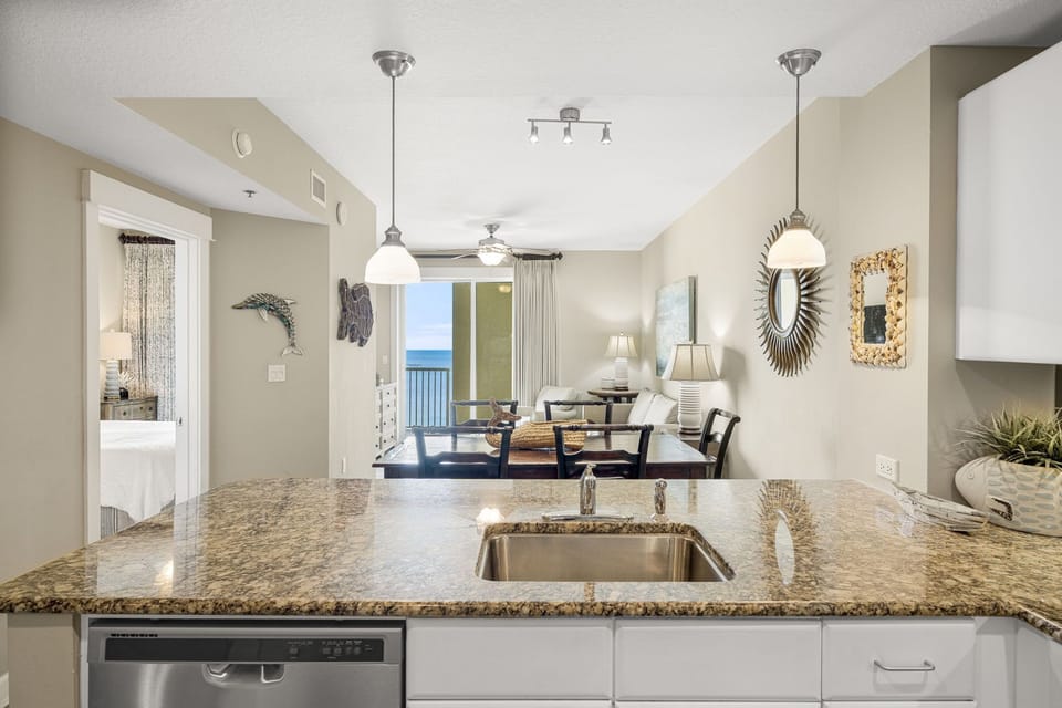 Modern kitchen with granite countertops overlooking a living area and ocean view balcony