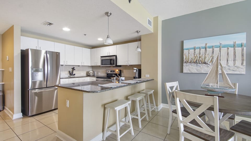 Modern kitchen with stainless steel appliances and a breakfast bar with seating.