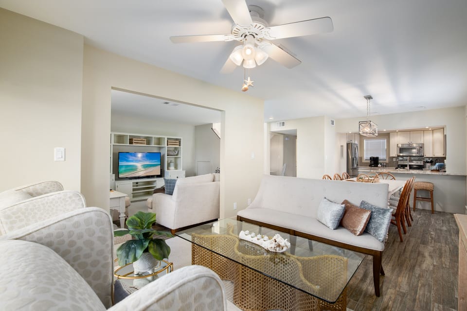 Relax in your spacious living area with plush seating, modern kitchen access, and entertainment center for perfect vacation comfort.