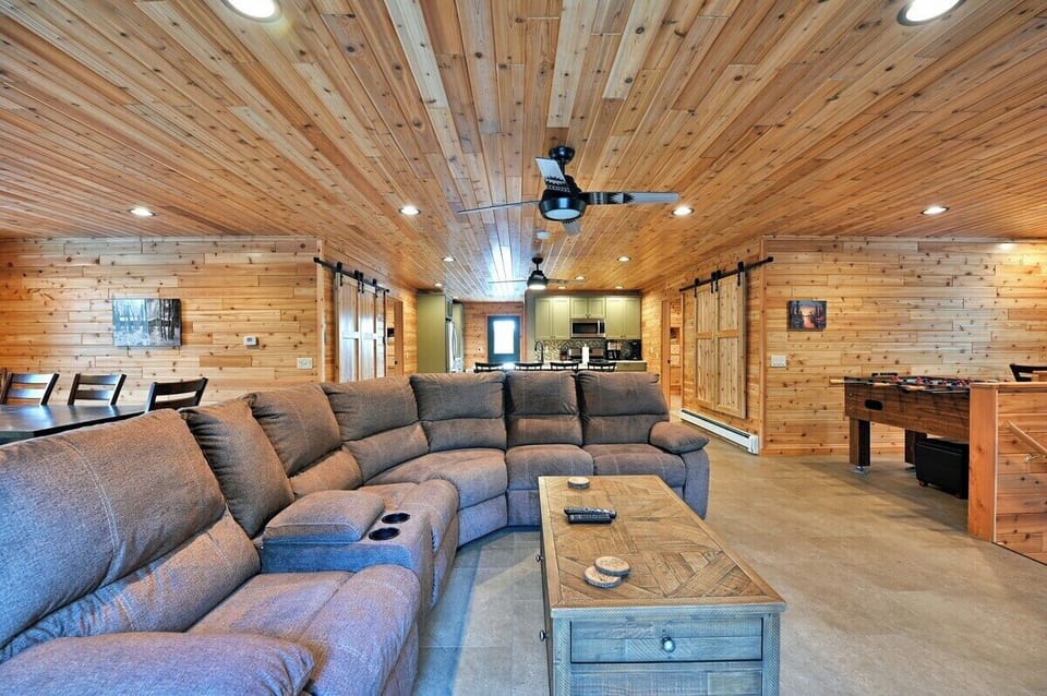The Taj Woodside has a cozy living room with wood-paneled walls, featuring a comfy brown sectional sofa to relax.