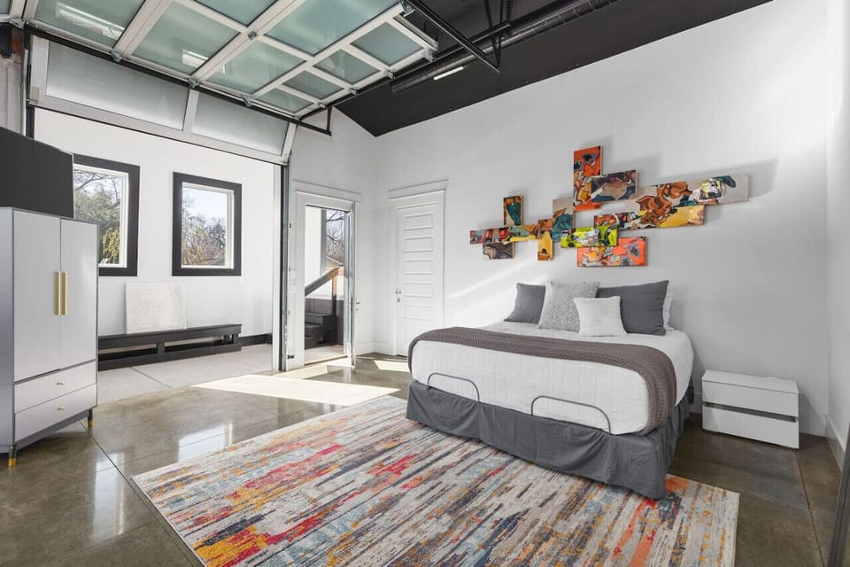 One of a kind primary bedroom with a king bed, Smart TV, and two garage doors you can open to lead to the patio space & hot tub.