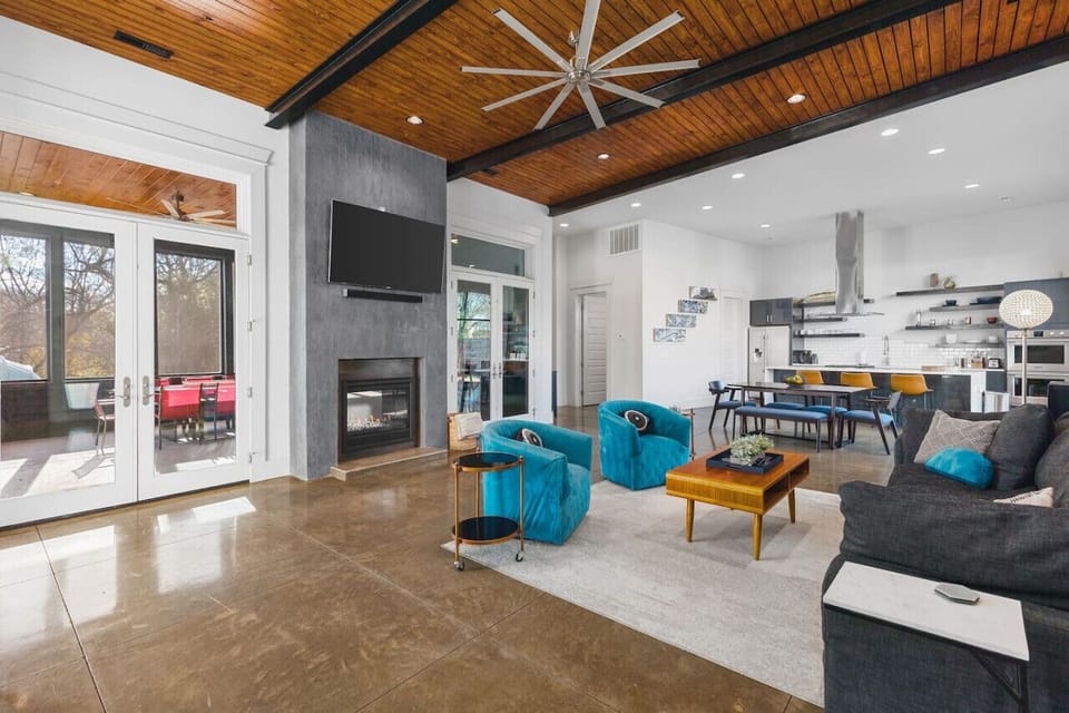 Massive living room with a large comfy couch, Smart TV, and fireplace connecting to the outdoor patio space.