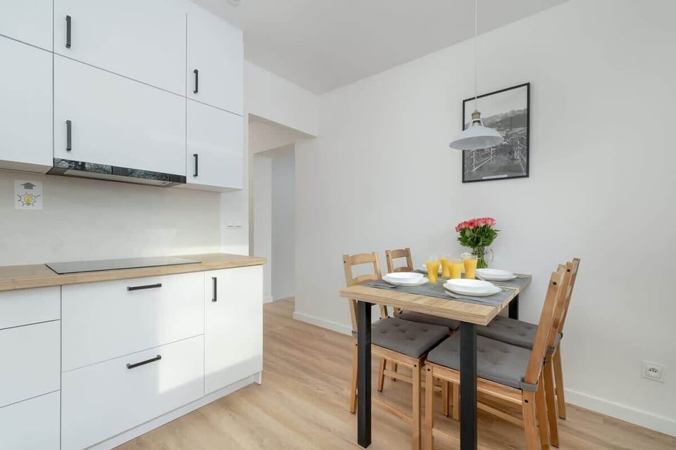 A dining area next to the kitchen with a wooden table and chairs, suitable for enjoying meals in a bright setting.

