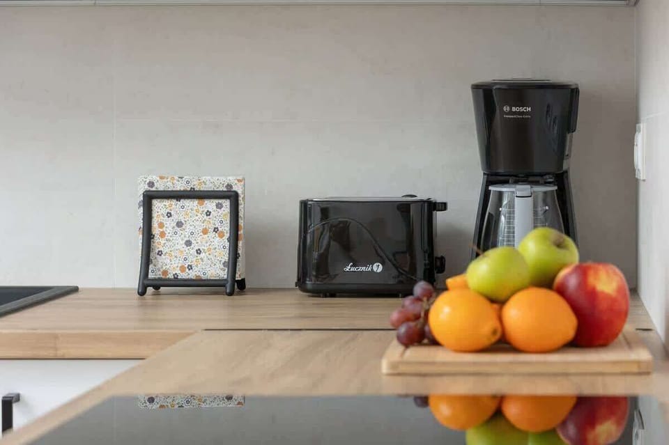 A countertop with a coffee maker, fruit bowl, and traditional decor, creating a cozy kitchen atmosphere.

