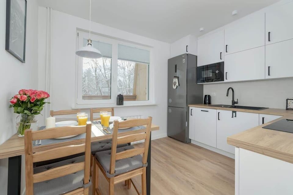 A modern kitchen and dining area with white cabinets, wooden countertops, and a table set for meals.

