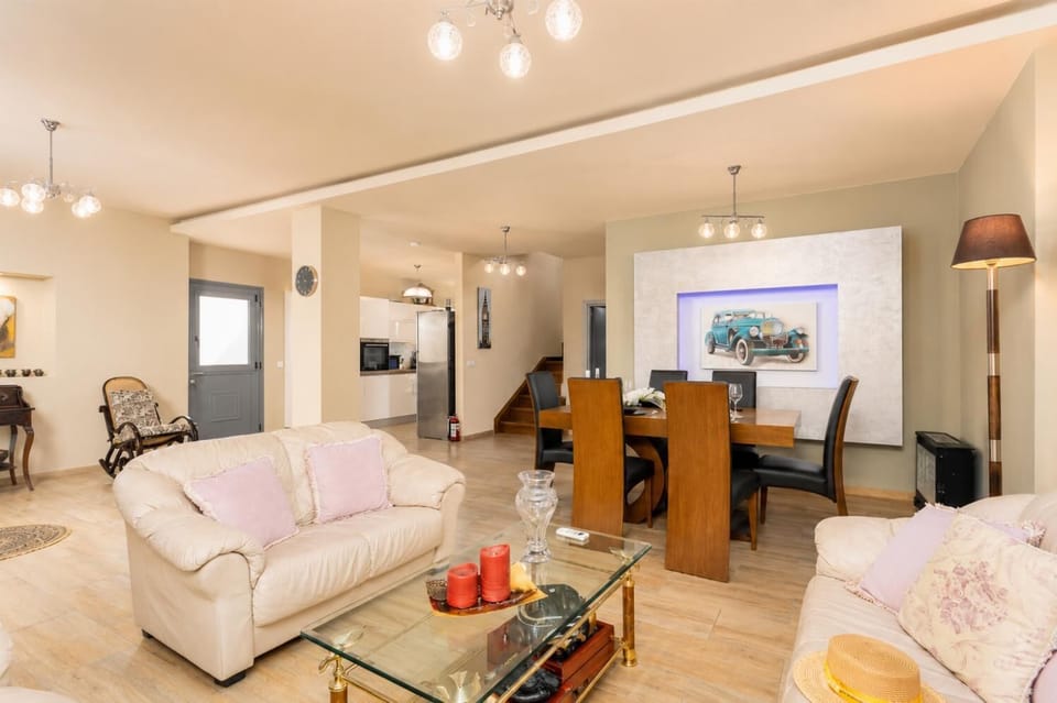Open-plan living room with sofas, dining area, kitchen, A/C, and WiFi internet