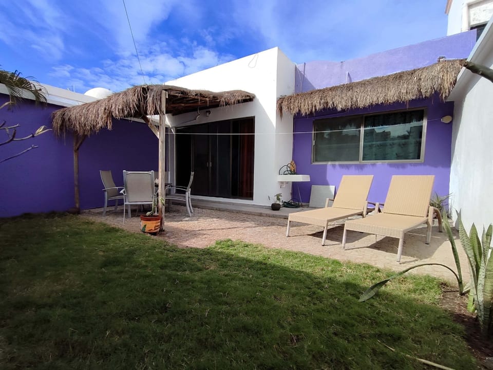 Back garden with sun loungers, table and chairs, pergola