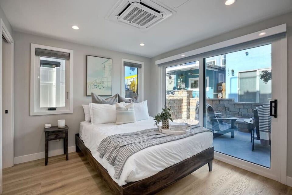 BEDROOM #1 – PRIMARY SUITE: Spacious primary bedroom with individual A/C and heating, a flat-screen smart TV with streaming, and a built-in armoire with drawers and hangers—creating a comfortable, organized retreat during your Mission Beach San Diego beac