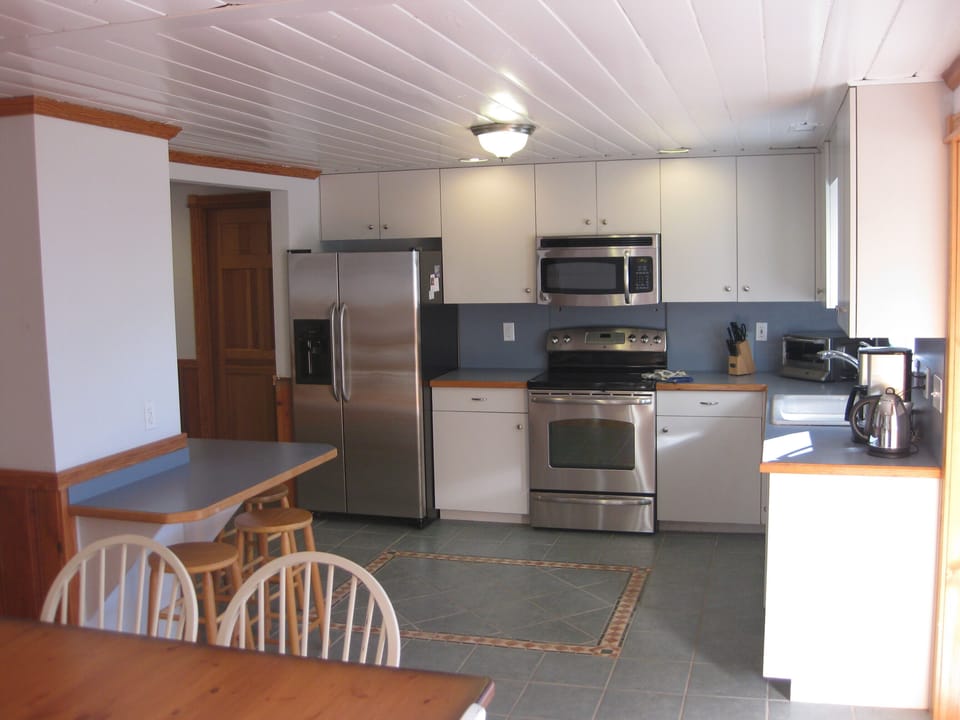 Full kitchen with seating at table and bar.