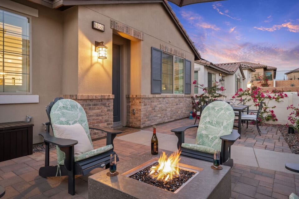 Cozy firepit lounge w/ cushioned chairs & warm lighting along the patio