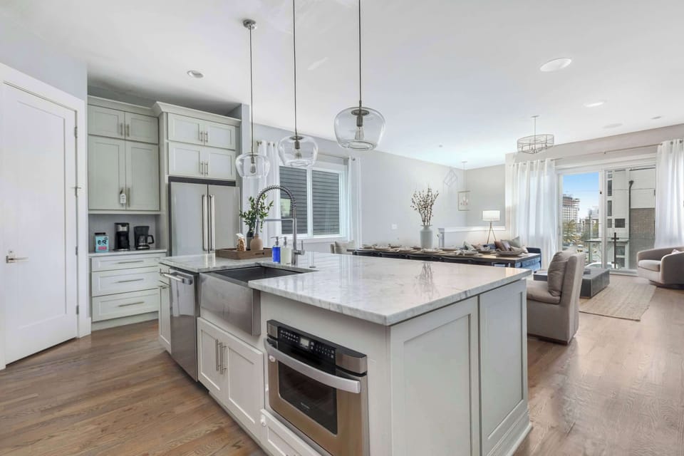 The kitchen features a farmhouse-style stainless steel sink paired with upgraded stainless steel appliances