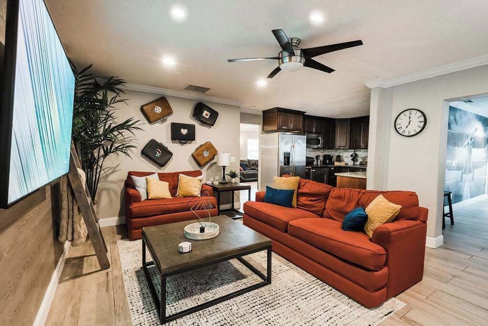 Discover a living room with personality—vintage suitcases add charm to the walls while a radiant globe sign lights up the space, blending comfort with a sense of wanderlust.