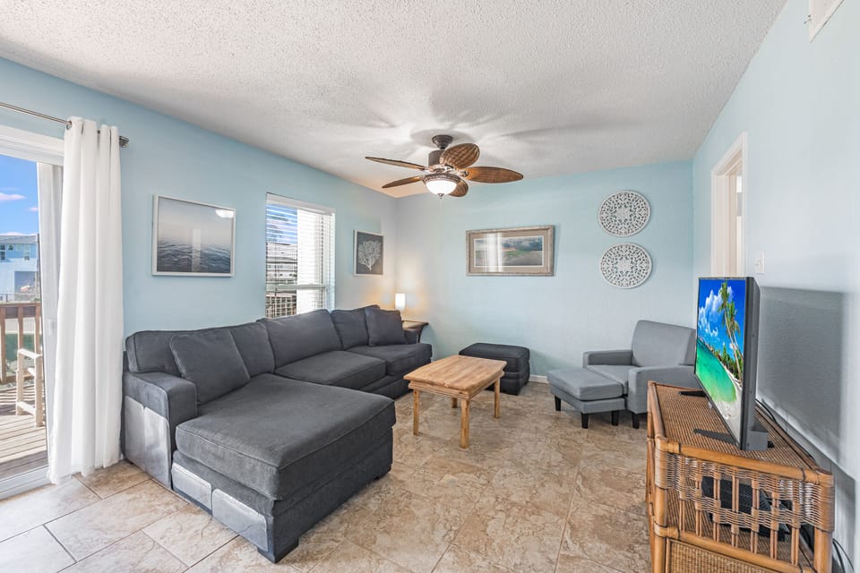 Unwind in your spacious living room with plush sectional seating, coastal decor, and ceiling fan comfort for ultimate relaxation.