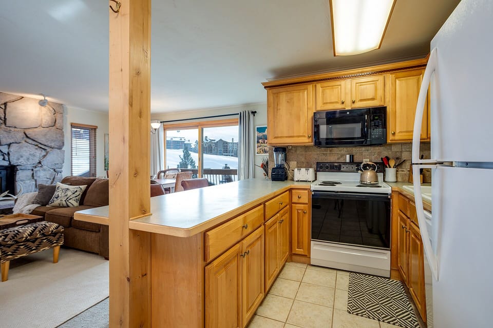 Your fully equipped kitchen invites home-cooked meals with mountain views through the window, perfect for cozy après-ski dining.