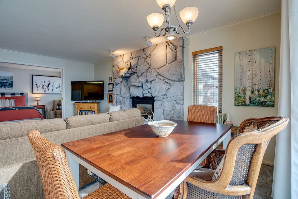 Gather around your beautiful dining table while the stone fireplace creates warmth and ambiance in this inviting open-plan space.