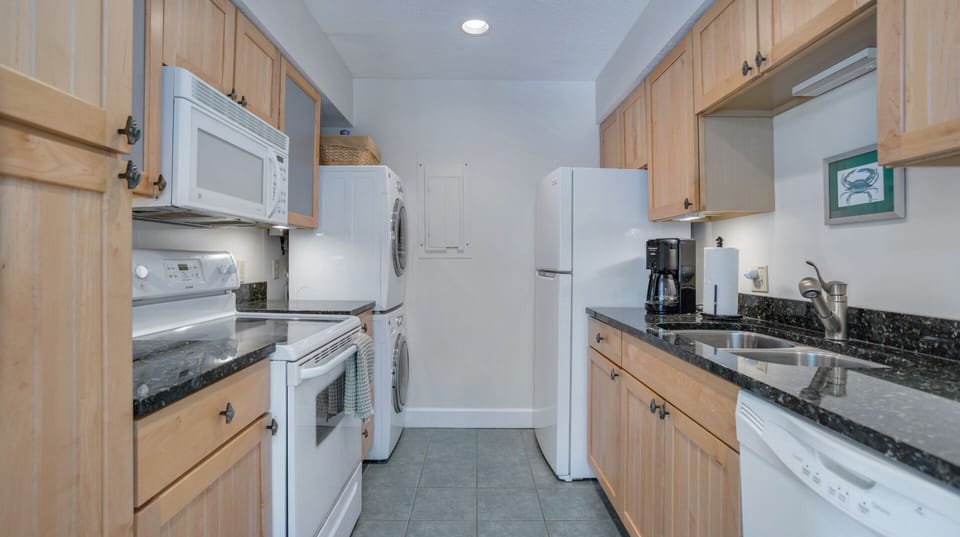 Light wood cabinetry pairs with granite countertops and full-size appliances, creating a clean, functional space