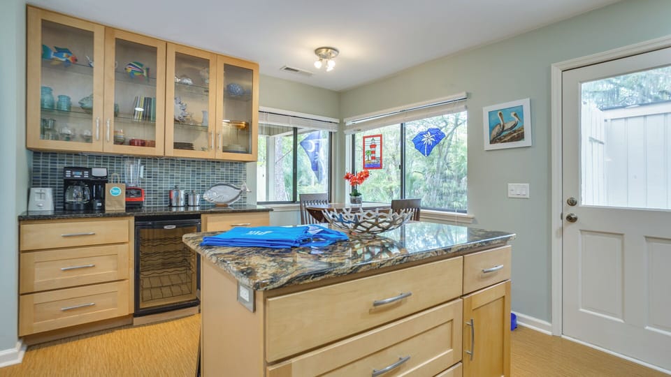 Large windows bring in natural light and showcase views of the surrounding greenery, adding to the room's welcoming atmosphere.