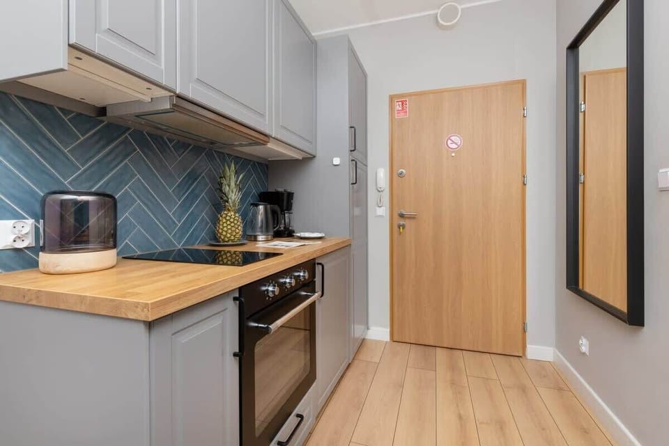 A contemporary kitchen with blue backsplash tiles, wooden countertops, and stainless-steel appliances for a stylish cooking space.

