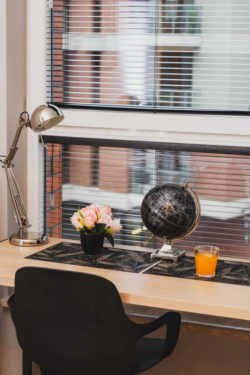 A workspace with a desk, chair, and decorative accessories by the window, providing a productive and bright environment.
