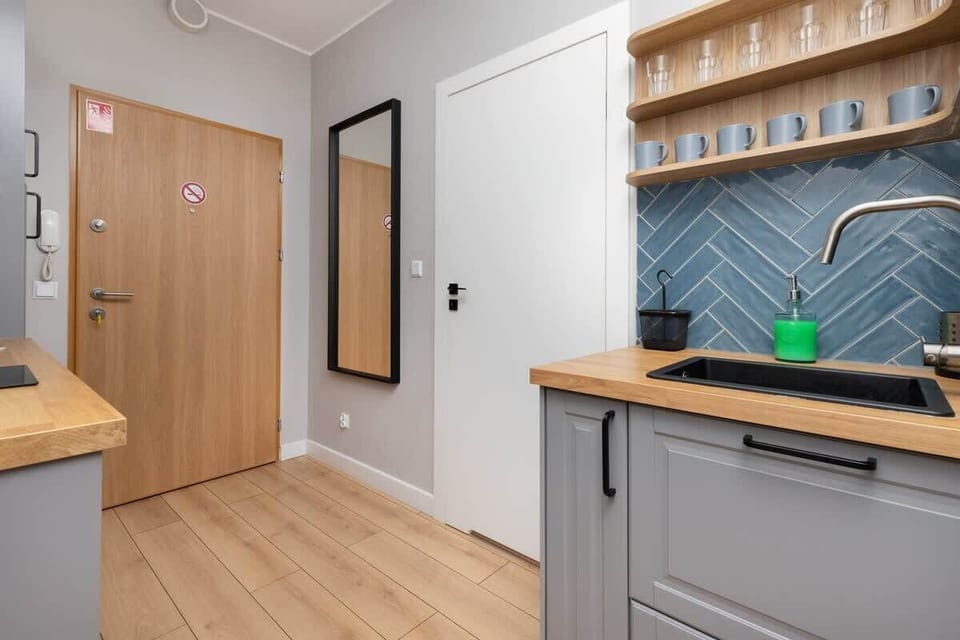 An entryway with wooden flooring, a minimalist coat rack, and a blue backsplash, offering a welcoming and organized entrance.
