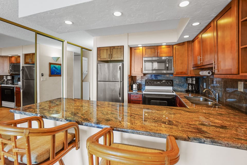 A functional kitchen with a blend of wood and granite, complemented by modern appliances and a well-lit dining area. Ideal for hosting and family meals.